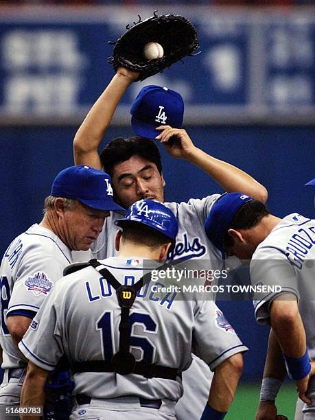 Los Angeles Dodgers' pitcher Kazuhisa Ishii of Japan wipes his brow while meeting with pitching coach Jim Colborn , catcher Paul Lo Duca, and second...