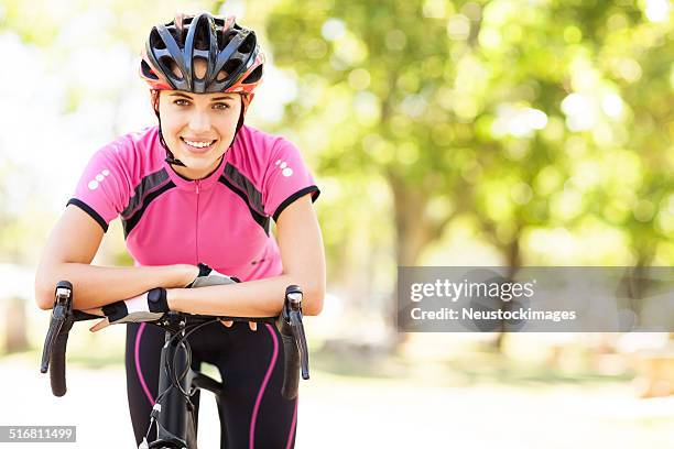 female cyclist in sportswear leaning on bicycle handlebars - biking athletic stock pictures, royalty-free photos & images