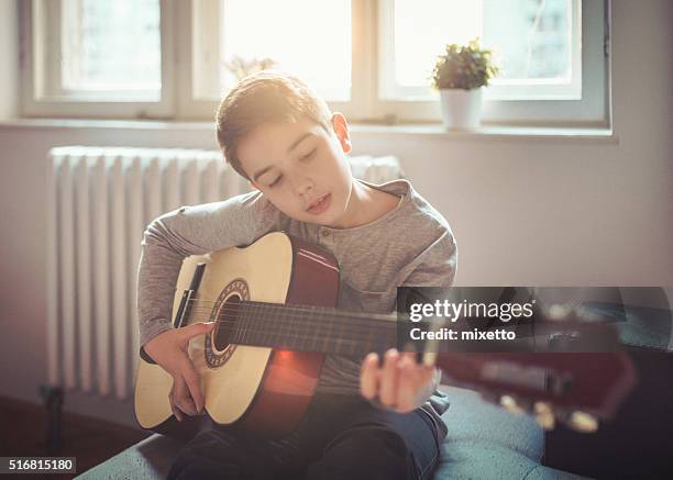 junge spielt gitarre zu hause - boy singing stock-fotos und bilder