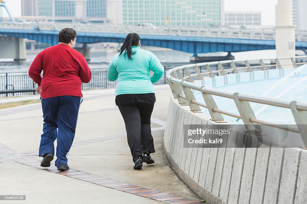 Rear view of two overweight people jogging