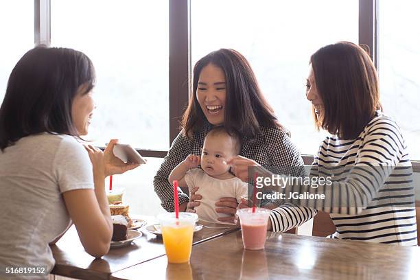 drei freunde und ein baby in einem café zusammen - asian family cafe stock-fotos und bilder