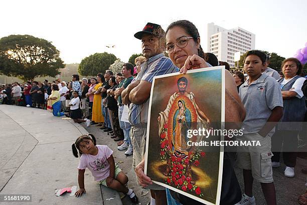 Woman displays a poster of Juan Diego during a mass at the Plaza Olvera in Los Angeles 31 July during an outdoor Mass. Pope John Paul II, in a...