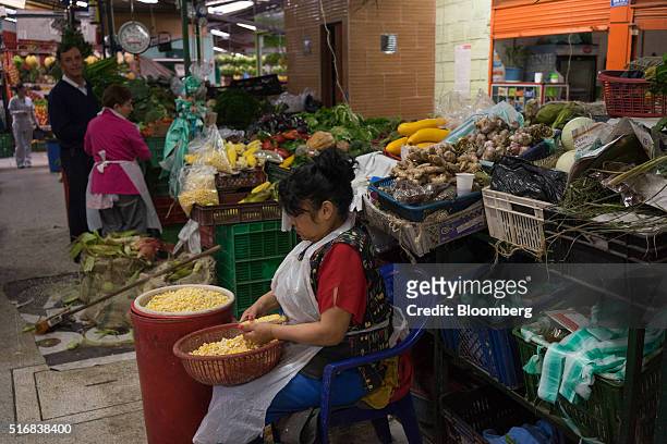 Woman prepares corn for sale at the Paloquemao market in Bogota, Colombia, on Wednesday, March 16, 2016. Colombia's central bank raised its benchmark...
