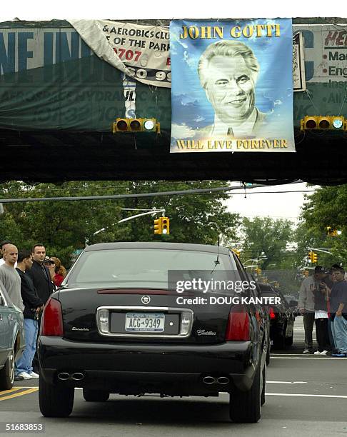 The face of John Gotti beams down from a sign near the Bergin Hunt and Fish Club in Queens, New York, 15 June 2002 as his funeral procession drives...