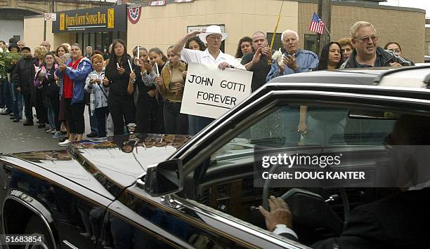 Carmine Romeo holds a sign reading "John Gotti Forever" and salutes the funeral procession of mob boss John Gotti in Queens, New York 15 June 2002 on...