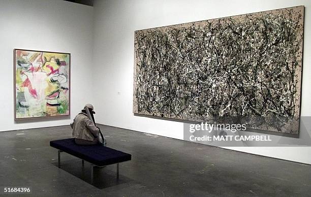 Woman sits on a bench between the paintings "One " by Jackson Pollock and "Pirate by Willem de Kooning during the press preview of the opening of the...