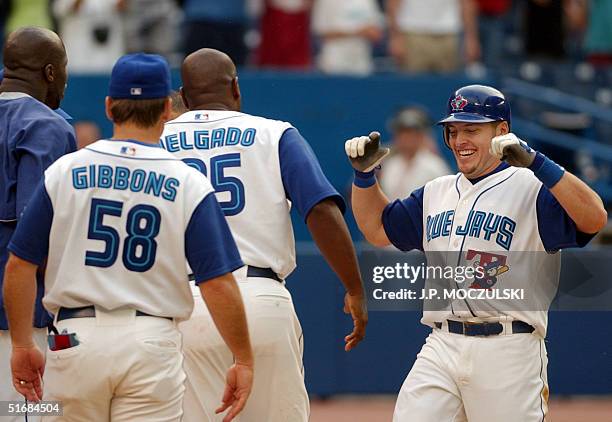 Jubilant Toronto Blue Jays' third baseman Eric Hinske is greeted at the plate by teammates after hitting the game-winning home run to right field in...