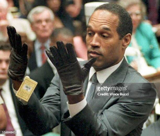 Simpson looks at a new pair of Aris extra-large gloves that prosecutors had him put on 21 June 1995 during his double-murder trial in Los Angeles....