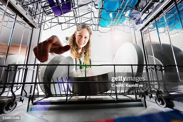 seen from inside dishwasher, cute smiling girl loading or unloading - wash the dishes stockfoto's en -beelden