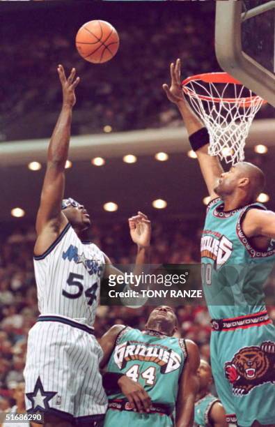 Orlando Magic forward Horace Grant goes over the top on Vancouver Grizzlies forward Kenny Gattison and center Benoit Benjamin for two points during...