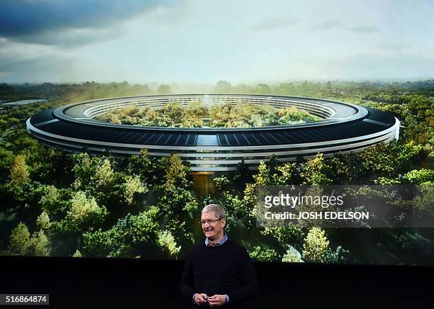 Apple CEO Tim Cook stands in front of a slide of the company's new campus which is under construction during a media event at Apple headquarters in...