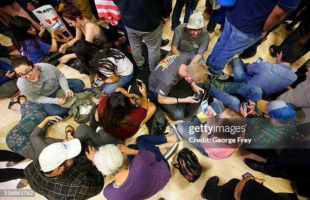 Bernie Sanders supporters sit on the floor looking at their smart phones during a campaign rally for Democratic presidential candidate Bernie Sanders...