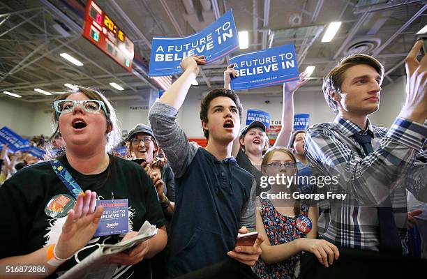 Supporters wave signs as Democratic presidential candidate Bernie Sanders speaks during a campaign rally at West High School on March 21, 2016 in...