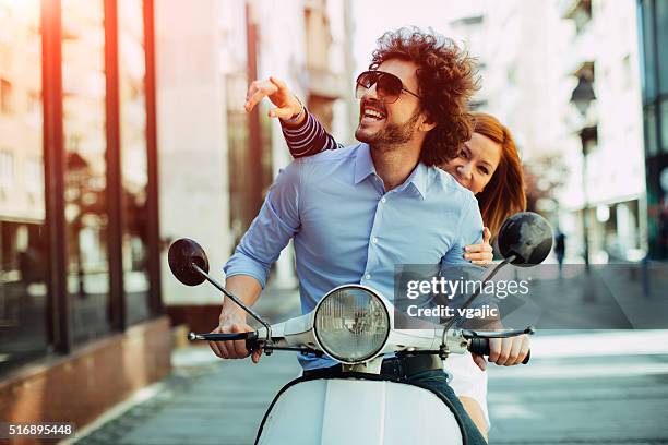 cheerful young couple riding on a motorbike. - scooter stockfoto's en -beelden