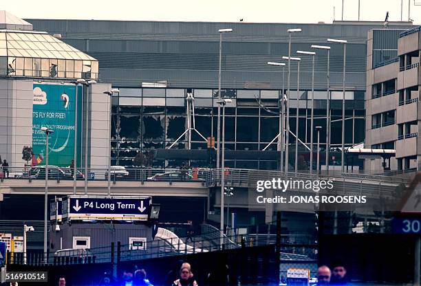 Picture taken on March 22, 2016 shows a Belgian police vehicle driving past passengers who are evacuating the Brussels Airport of Zaventem. At least...