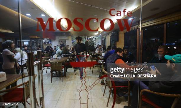 Syrians sit at the "Moscow Cafe" in the Dahiya Tishreen neighbourhood of the coastal city of Latakia, a stronghold of Syria's president, on March 17,...