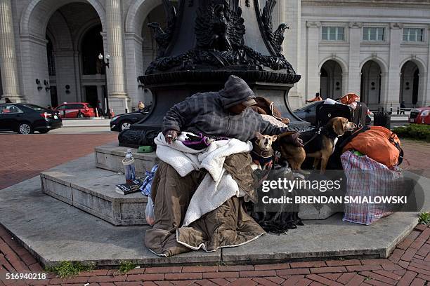 Woman sits with her dogs outside Union Station March 22, 2016 in Washington, DC. / AFP / Brendan Smialowski