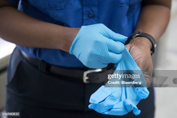 Transportation Security Administration officer puts on sterile gloves in the TSA pre-check area at Dulles International Airport in Dulles, Virginia,...