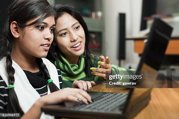 happy teenage asian girls of different ethnicity using laptop together. - girl black hair room stock pictures, royalty-free photos & images