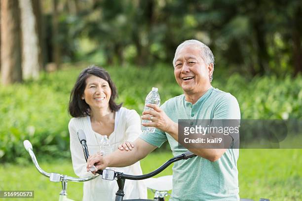 senior couple riding bicycles - japanese senior couple stockfoto's en -beelden