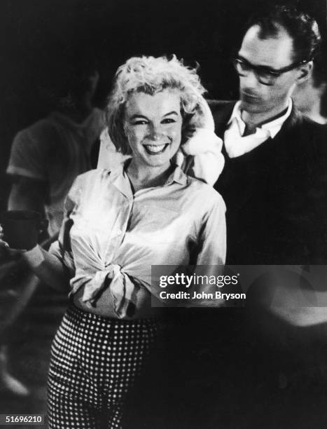 American actress Marilyn Monroe laughs while her husband, American playwright Arthur Miller, dries her hair after a dance rehearsal for director...