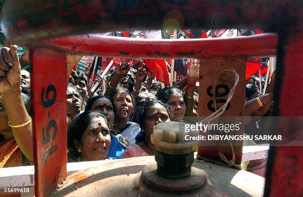 Activists of the Indian political party All India Anna Dravida Munnetra Kazhagam are seen through the handles of a gas cylinder as they shout slogans...