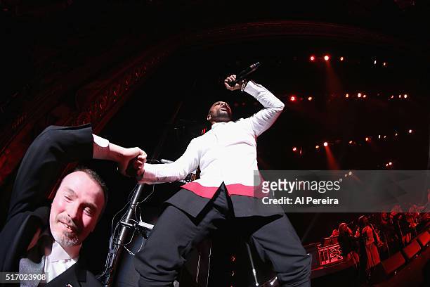 Kirk Franklin holds the hand of a security guard when he performs his "Twenty Years In One Night" show at Kings Theatre on March 22, 2016 in New York...