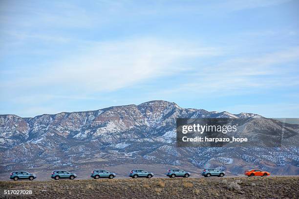 row of blue suv's following an orange car. - car parade stock pictures, royalty-free photos & images