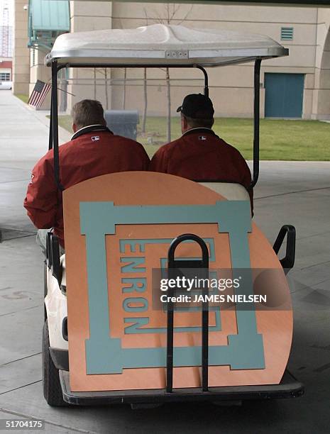 Houston Astros employees Lowell Matheny and David McKenzie drive off in a golf cart with a sign that they just removed from Astros Field which was...