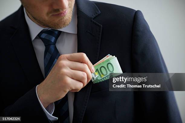 Berlin, Germany In this Photo Illustration a person puts euro bills in the pocket of his jacket on March 23, 2016 in Berlin, Germany.