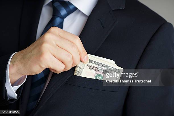 Berlin, Germany In this Photo Illustration a person puts dollar bills in the pocket of his jacket on March 23, 2016 in Berlin, Germany.