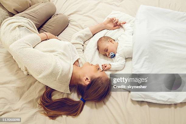 mother and baby sleeping on the bed. - sleeping baby stock pictures, royalty-free photos & images