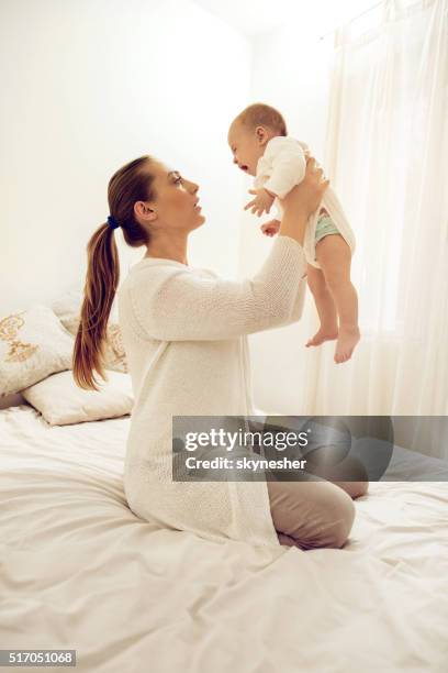 young mother holding her baby who is crying. - moms crying in bed stockfoto's en -beelden