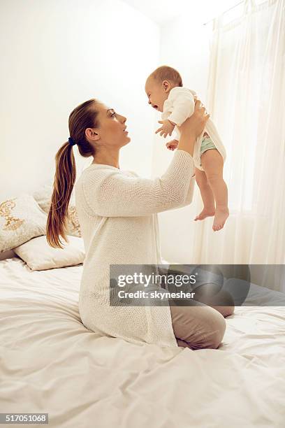 young mother holding her baby who is crying. - moms crying in bed stock pictures, royalty-free photos & images