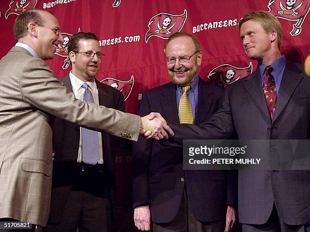 Tampa Bay Buccaneers new Head Coach Jon Gruden shakes hands with Bucaneer Joel Glazer, as his brother Bryan Glazer and father Malcom Glazer look on...