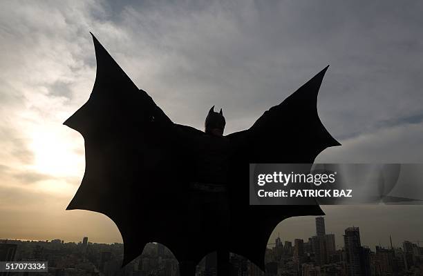 Lebanese model dressed as Batman plays on the rooftop of a building during a photoshoot in the capital Beirut on March 23, 2016. / AFP / PATRICK BAZ