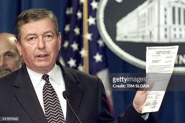Attorney General John Ashcroft holds up the twelve page criminal complaint filed with the United States Eastern District Court of Virginia against...