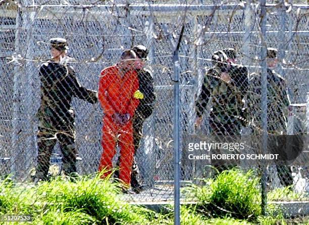 One of the 80 Al-Qaeda and Taliban detainees wearing an orange jump suit can be seen in his cell at Camp X-Ray surrounded by heavy security at the...