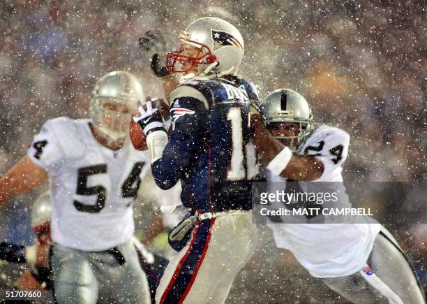 New England Patriots quarterback Tom Brady takes a hit from Charles Woodson of the Oakland Raiders on a pass attempt in the last two minutes of the...