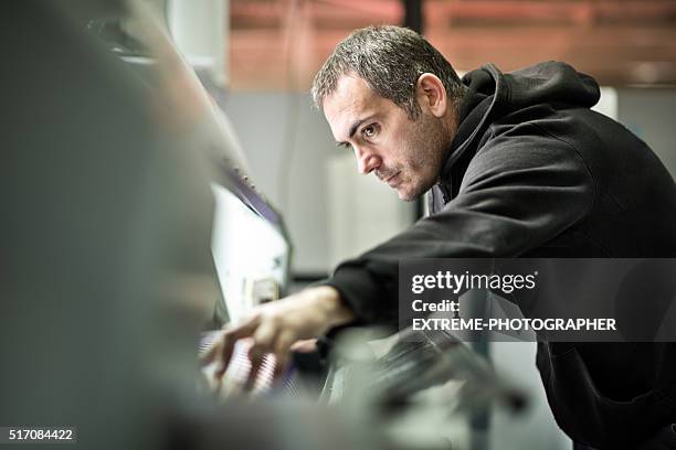 homme travaillant sur l'imprimante immense - équipement à base de papier photos et images de collection