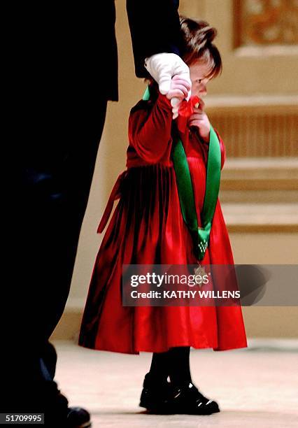 Two-year-old Patricia Smith holds her father's gloved hand 04 December 2001 in New York after accepting the New York Police Department's highest...