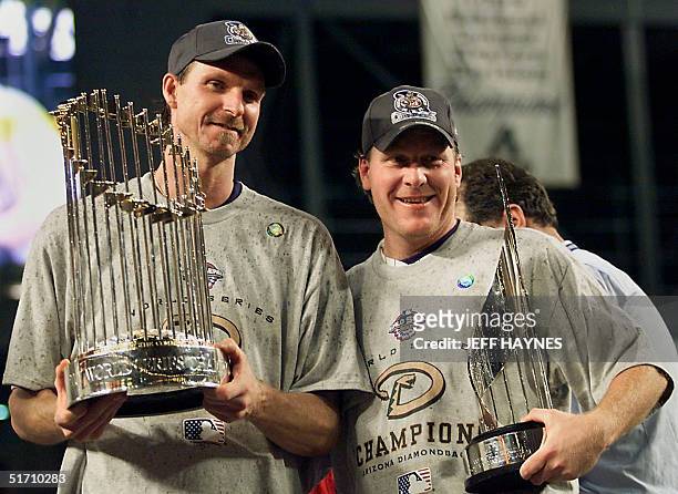 World Series co-MVPs Arizona Diamondbacks pitchers Randy Johnson and Curt Schilling hold the World Series winner's trophy and the MVP trophy during...
