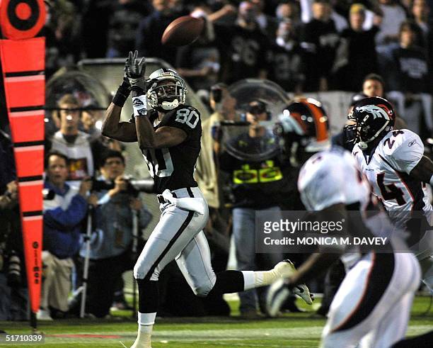 Oakland Raiders wide-receiver Jerry Rice hauls in a catch from Raiders quarterback Rich Gannon as Denver Broncos cornerback Deltha O'Neal and Broncos...