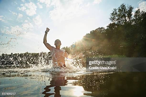 man splashing water in lake - man splashed with colour fotografías e imágenes de stock