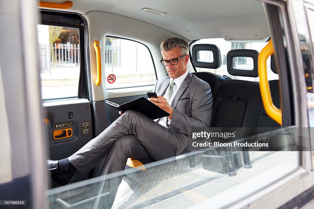 Business man using a smart phone in a Taxi