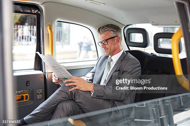 business man reading a paper in a taxi - open newspaper stock pictures, royalty-free photos & images