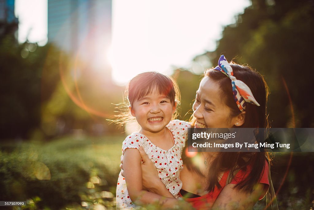 Mom playing joyfully with toddler in park