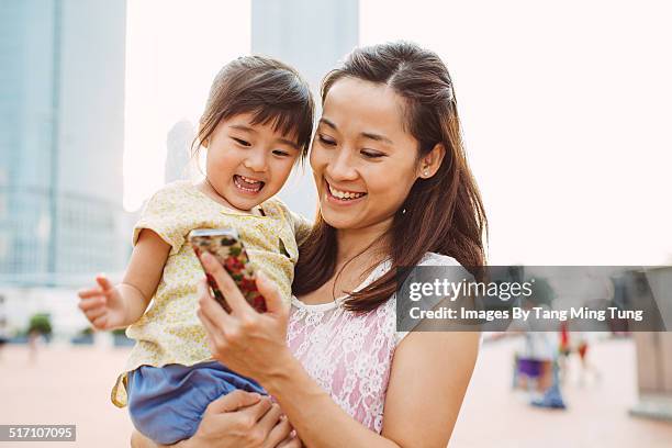 mom using smartphone joyfully with toddler - baby mobile 個照片及圖片檔