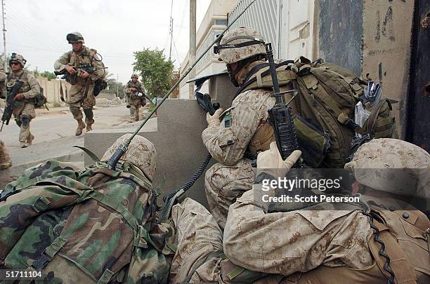 Marines of Bravo Company, 1st Battalion 3rd Marines take cover while trying try to clear a street November 9, 2004 in Fallujah, Iraq. On the...
