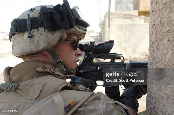 Corporal Christopher DeBlanc of Spotsylvania, Virginia scopes around a corner, as US Marine scouts of the Light Armor Reconnaissance try to clear a...